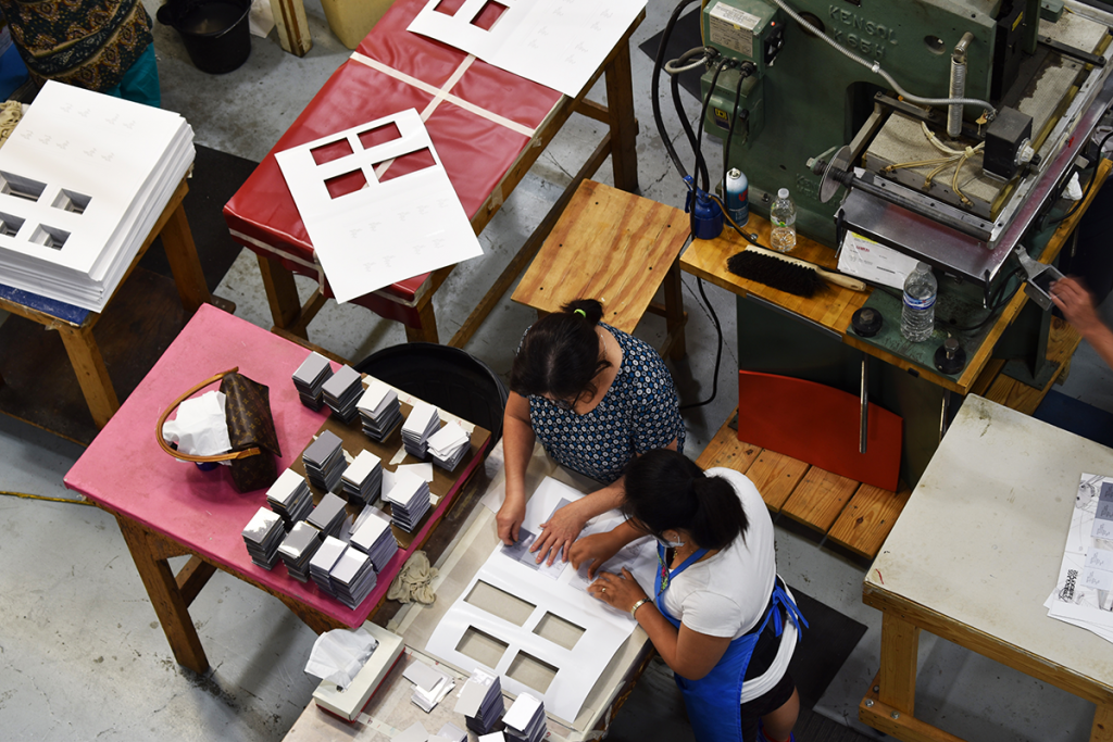 two workers putting fabric swatches onto page